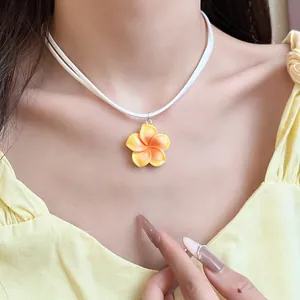 Close-up van een gele Hawaiiaanse frangipanibloem hanger aan een witte koordketting
