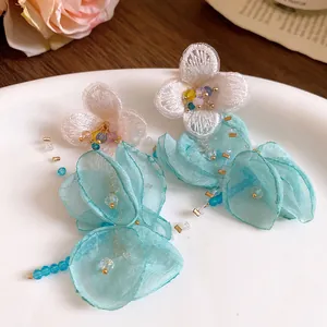 Detailed view of handmade chiffon flower earrings with turquoise fabric petals and beads.