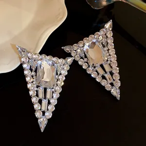 Vista detallada de pendientes triangulares de plata con incrustaciones de pedrería