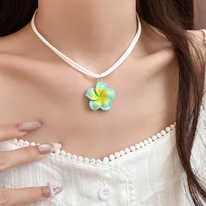 Close-up van een Hawaiiaanse plumeria bloem hanger ketting in mintgroen en geel