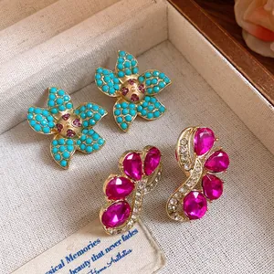 Close-up of elegant vintage flower earrings and fuchsia crystal studs in a jewelry box