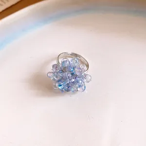 Primo piano di un delicato anello a grappolo con perle iridescenti viola e blu