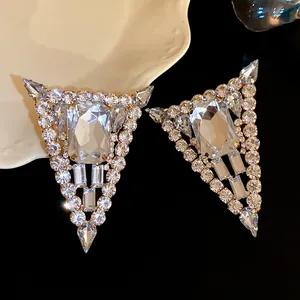 Detalle de elegantes pendientes de botón triangulares de plata con brillantes diamantes