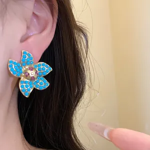 Detailed view of vintage gold flower earring with turquoise beads and pink center