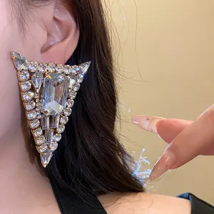 Primer plano de un elegante pendiente de triángulo con cristales de brillo lujoso