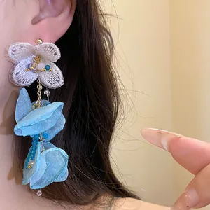 Close-up detail of elegant white chiffon flower tassel earrings with blue petals worn by a model