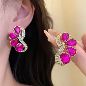 Close-up of vintage gold earrings with magenta crystals and sparkling rhinestones