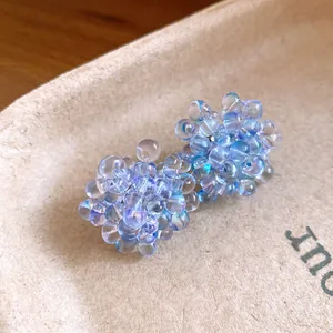Dettaglio macro di orecchini a grappolo di perline blu chiaro cangianti ed eleganti