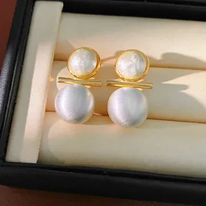 Detailed shot of elegant brushed gold and silver stud earrings with pearls in a box