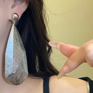 Primo piano di un elegante orecchino a goccia con glitter argento indossato da una modella.