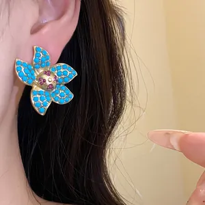 Close-up of vintage flower stud earring with turquoise-style beads on model's ear