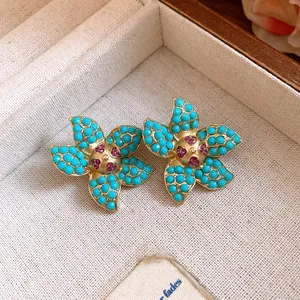 Macro detail of vintage floral stud earrings featuring turquoise beads and gems
