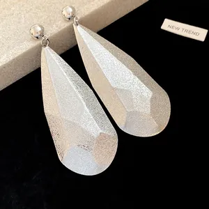 Dettaglio macro di eleganti orecchini pendenti a goccia d'argento con finitura glitterata