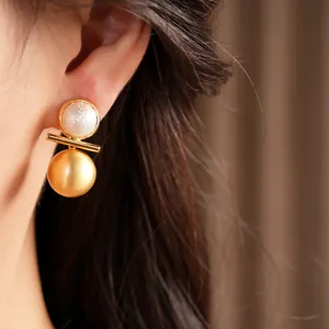 Macro close-up showing elegant real gold plated brushed pearl stud earrings on an ear