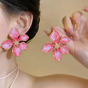 Dettaglio di orecchini a fiore in smalto rosa con bordi dorati su una modella asiatica