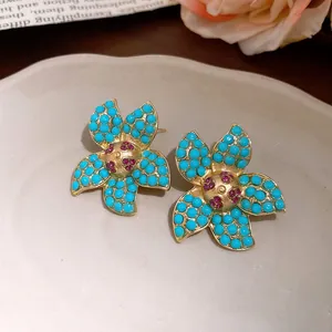 Detailed view of vintage-style floral earrings with turquoise stones and gold-toned texture.