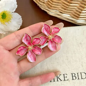 Primo piano dettagliato di orecchini a lobo a fiore in smalto rosa e oro
