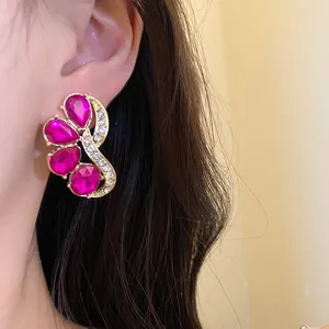 Close-up of vintage gold-tone stud earring featuring magenta teardrop crystals and clear rhinestones