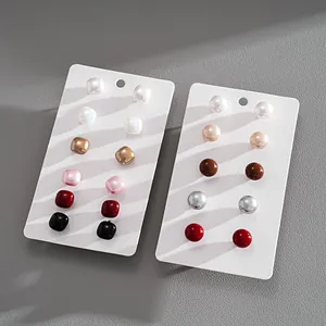Close-up of 12-piece faux pearl earring set featuring square and round studs on white display cards