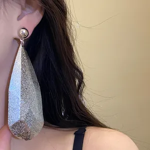 Dettaglio degli orecchini a goccia in argento testurizzato con finitura glitterata