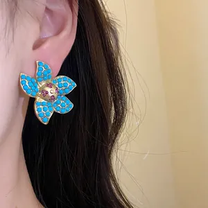 Detailed view of vintage flower stud earrings with turquoise and pink stones on model's ear