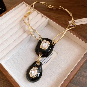 Close-up of a vintage gold-toned necklace with black enamel pendants and clear crystals.