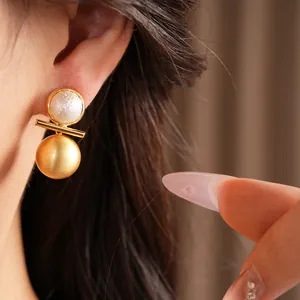 Close-up of golden brushed earrings with pearl detail, elegant and luxury jewelry.