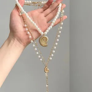 Detailed view of layered necklace featuring elegant faux pearls and gold conch pendants.