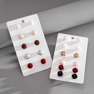 Close-up of faux pearl stud earring sets in round and square shapes on white cards
