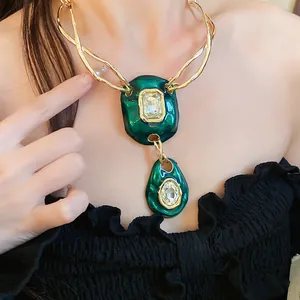 Macro view of vintage gold necklace featuring green enamel pendants and sparkling crystals