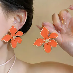 Dettaglio degli orecchini a fiore arancione vivace con centro in strass scintillanti