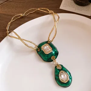 Macro detail of retro emerald green pendants with sparkling crystal accents on gold chain.