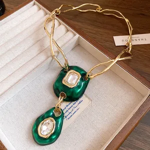 Detail of vintage gold-tone necklace featuring textured green crystal pendants.