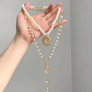 Detail shot of bohemian layered pearl necklace set with elegant gold conch pendant