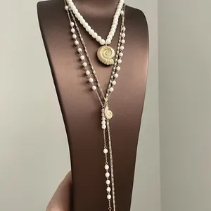 Elegant close-up of a layered long necklace featuring a gold nautilus pendant and white pearls