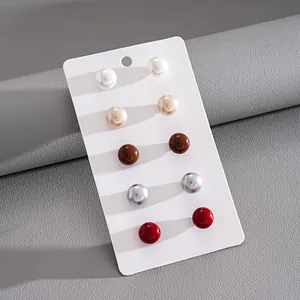 Macro view of a 5-pair colorful minimalist faux pearl stud earring set on white card