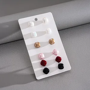 Macro view of a 12-piece set of square faux pearl stud earrings in diverse colors