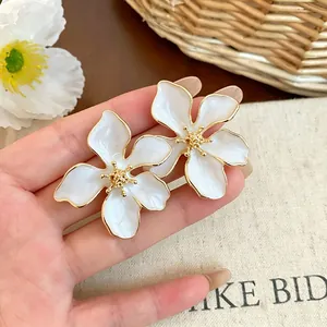 Dettaglio ravvicinato di orecchini a lobo a fiore in smalto bianco con bordo oro elegante
