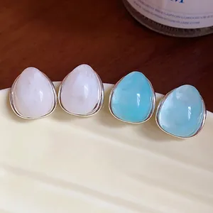 Elegantes pendientes de acrílico en forma de gota en blanco y azul en plato decorado