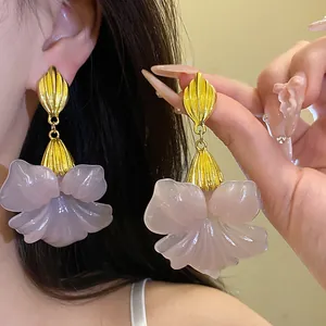 Detailed macro view of vintage-style pink resin flower drop earrings with gold finish.