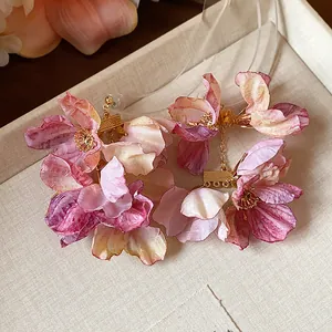 Nahaufnahme eleganter Stoffblumen-Ohrringe mit rosa und lila Farbverlauf-Blüten