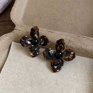 Primo piano di eleganti orecchini vintage a fiore in resina tartarugata con motivi scuri