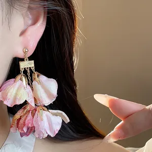 Detaillierte Nahaufnahme von eleganten rosa Stoffblüten-Ohrhängern, getragen von einem Modell