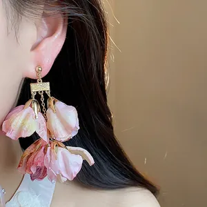 Detailansicht eleganter rosa Stoffblumen-Ohrringe, getragen von einem Modell