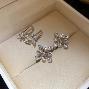 Macro view of silver flower ear cuffs with sparkling zircon stones in a gift box