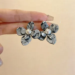 Primo piano di orecchini vintage a fiore in resina con motivo marmorizzato bianco e nero
