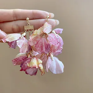 Detailansicht der ätherischen rosa Stoffblumenohrringe mit strukturierten Goldakzenten.