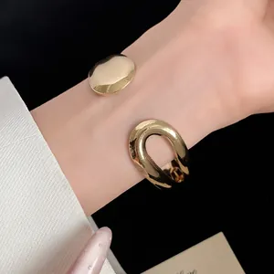 Detailed close-up of a minimalist gold-finished open cuff bangle on a woman's wrist