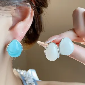 Elegantes pendientes de gota de acrílico en azul y blanco, detalle real en la oreja