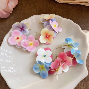 Close-up of colorful fabric flower hoop earrings on a white decorative plate.